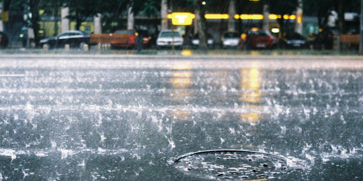 photo of rainfall on city street and manhole cover