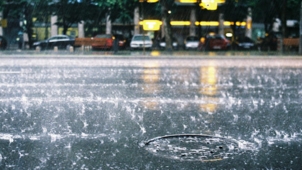 photo of rainfall on city street and manhole cover