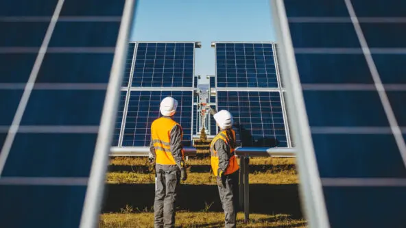 male & female solar O&M staff inspect solar panels mounted on a track; looking for hail damage