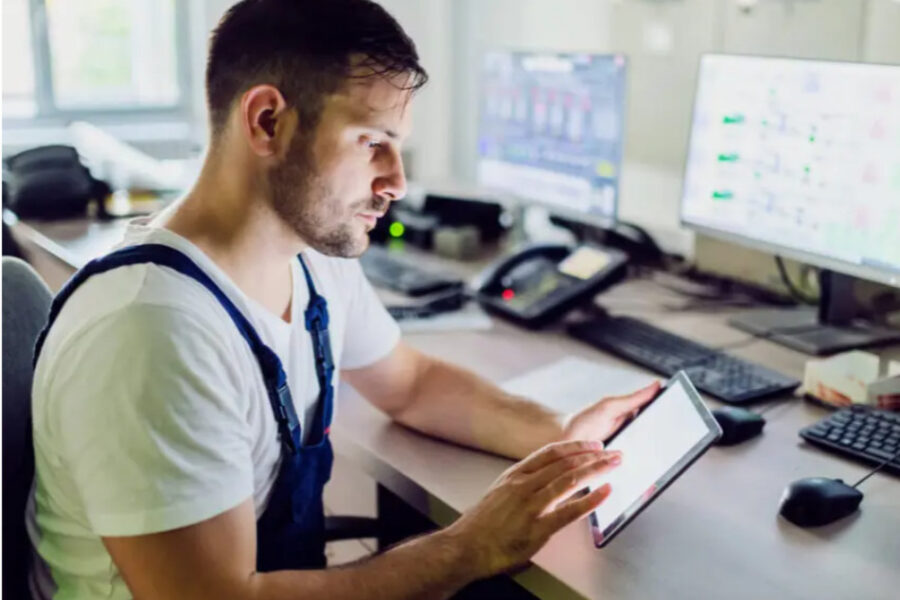 photo of male operator on duty using a tablet in a control room with multiple computer monitors