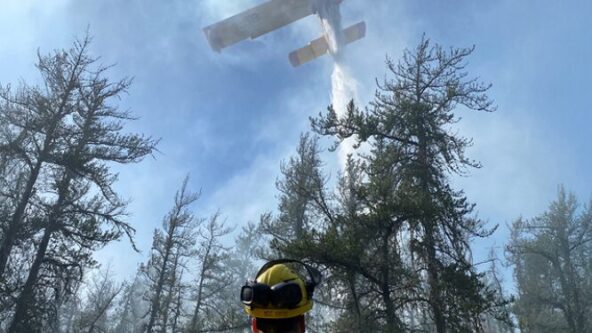 photo Manitoba Wildfire Service crew leader watches aircraft deliver a water drop